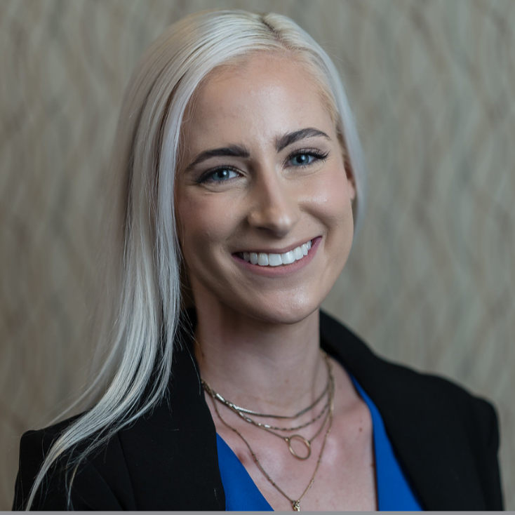 Μια χαμογελαστή γυναίκα που φορά ένα μαύρο παλτό πάνω από μια μπλε μπλούζα