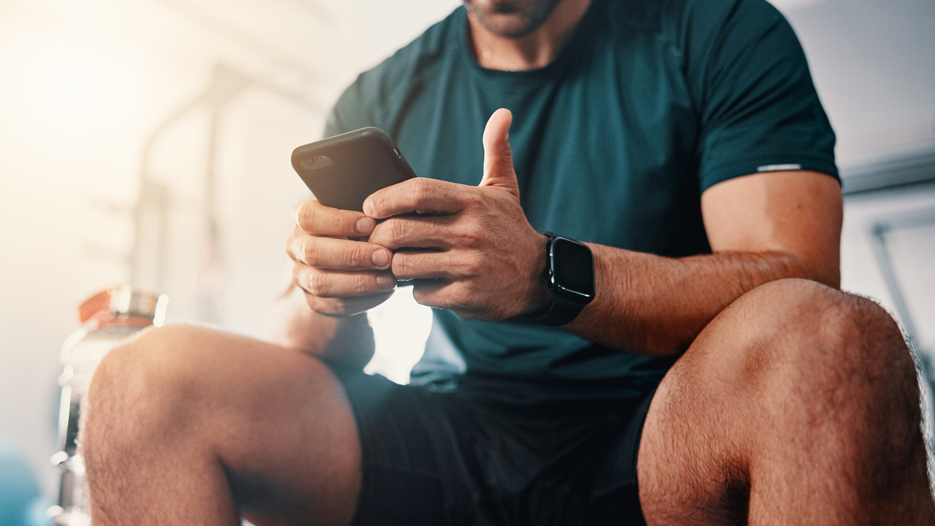 ένας άντρας με εξοπλισμό γυμναστικής κάθισε και κοίταξε στο τηλέφωνο