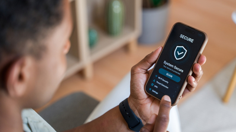 άνθρωπος που κοιτάζει το smartphone με την κατάσταση ασφαλούς σημάδι επιλογής στην οθόνη