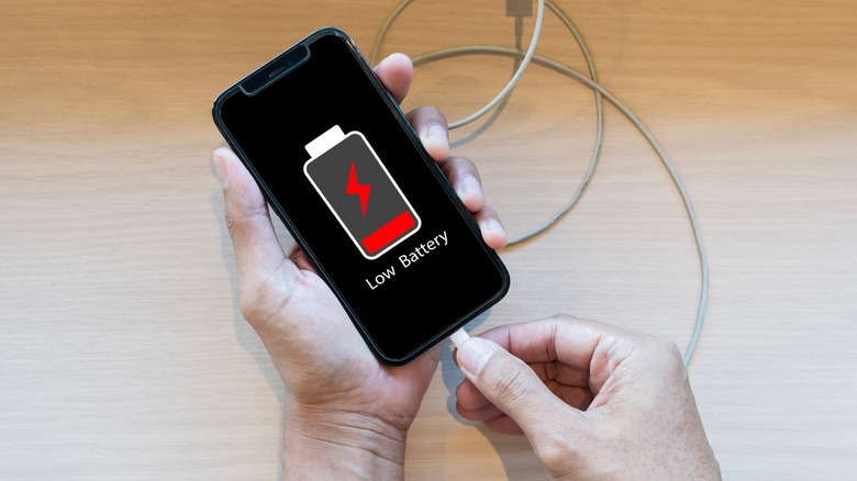 Ένα smartphone είναι συνδεδεμένο ενώ εμφανίζει ειδοποίηση χαμηλής μπαταρίας.