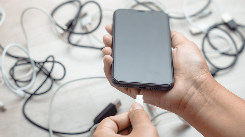 Ένα άτομο που συνδέει ένα καλώδιο USB σε ένα smartphone.