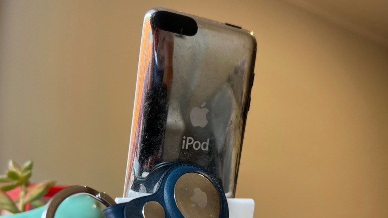 Στο πλαίσιο, το πίσω μέρος ενός iPod touch, ένα AirTag και ένα μικρό φυτό
