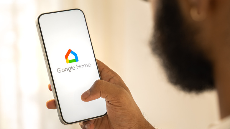 άνδρας που κρατά το smartphone με το λογότυπο google home ορατό σε αυτό