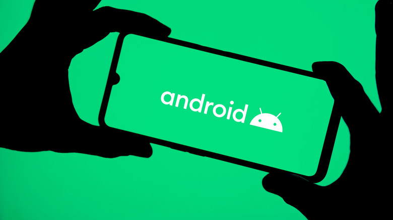Το λογότυπο Android σε ένα smartphone κρατιέται ψηλά από δύο χέρια.