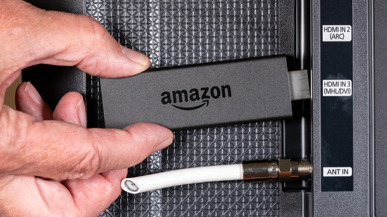 Ένα άτομο που συνδέει ένα Amazon Fire TV Stick σε μια έξυπνη τηλεόραση.