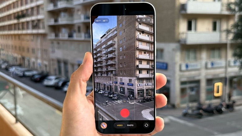 Ένα χέρι που κρατά ένα iPhone έτοιμο να εγγράψει ένα βίντεο.